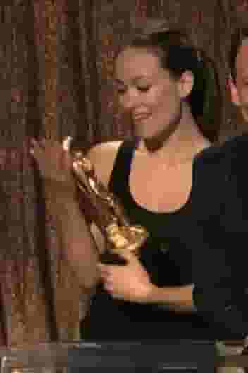 Olivia Wilde puts a trophy in her mouth at an awards show
